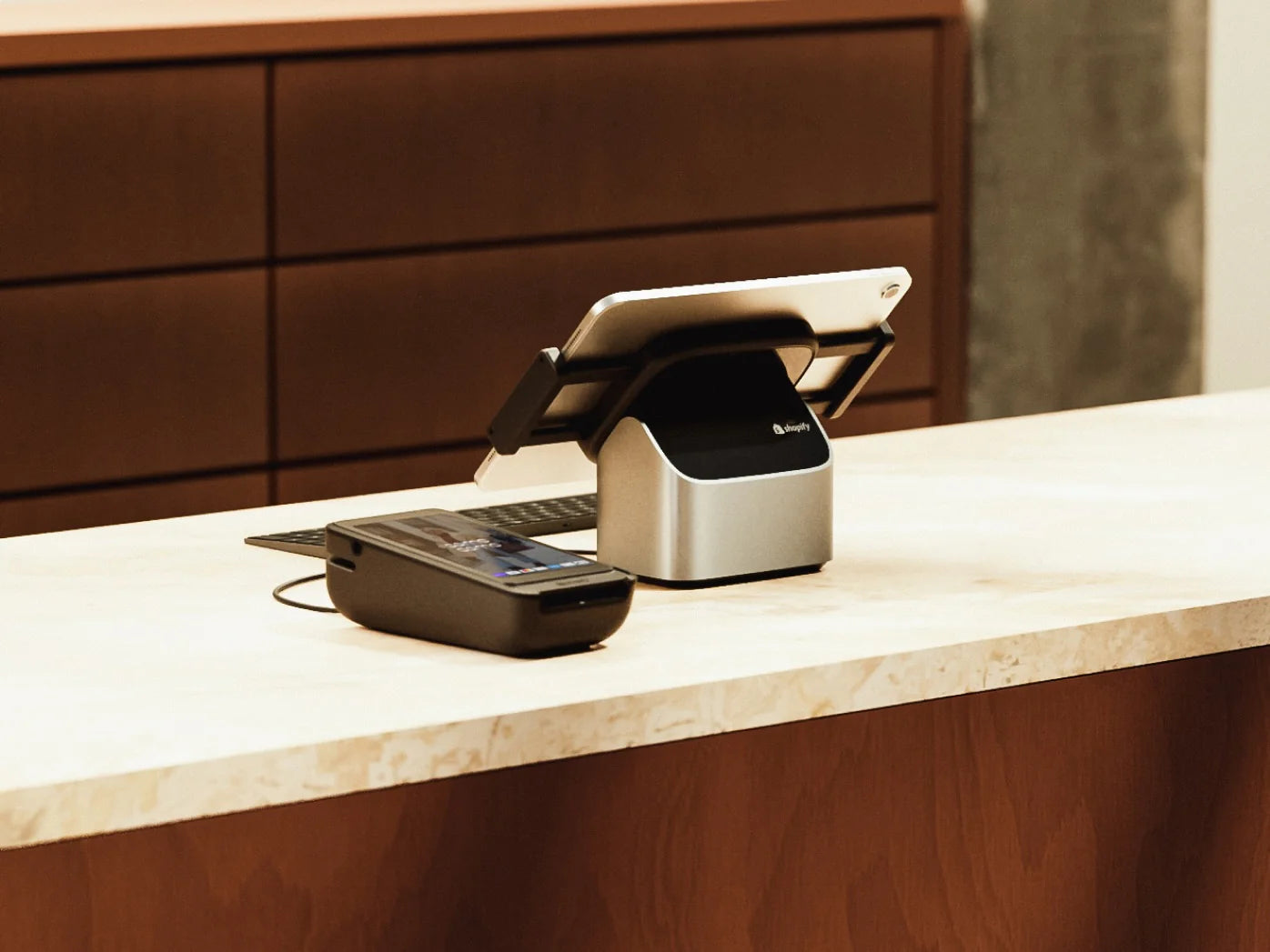 Terminal de paiement Shopify POS et tablette sur un comptoir en bois et marbre